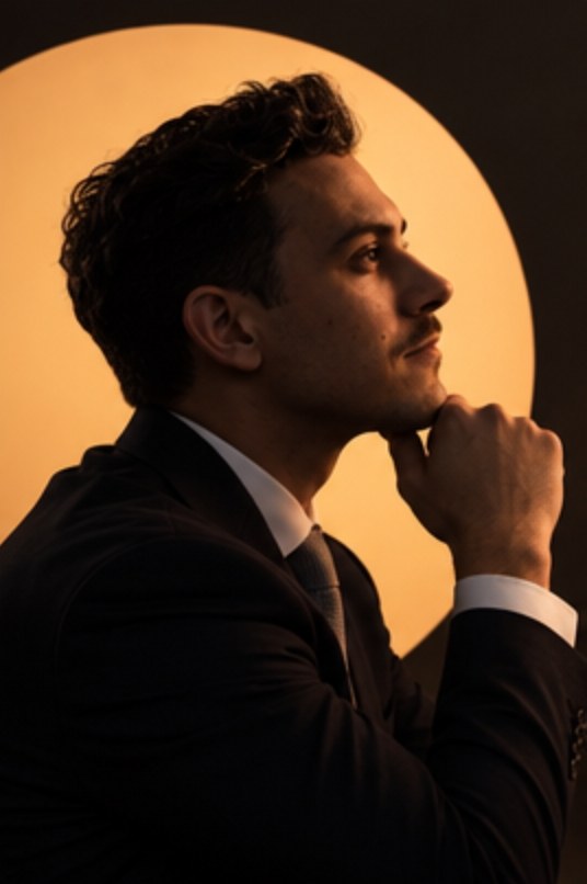 Maxime in profile, hand on chin, thinking